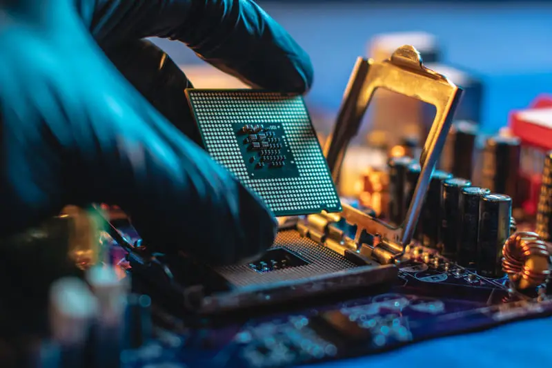 Ein Computerchip wird auf einem Mainboard eingesetzt, während eine Reparatur durchgeführt wird.